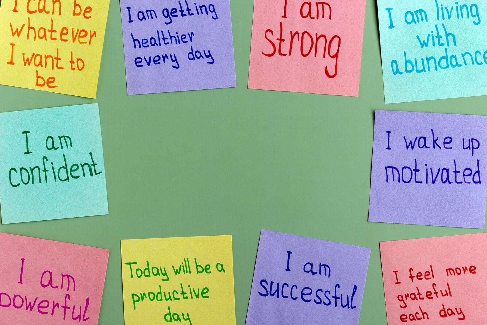 Positive affirmations for every day - words on multi-colored on paper for notes on a green background.